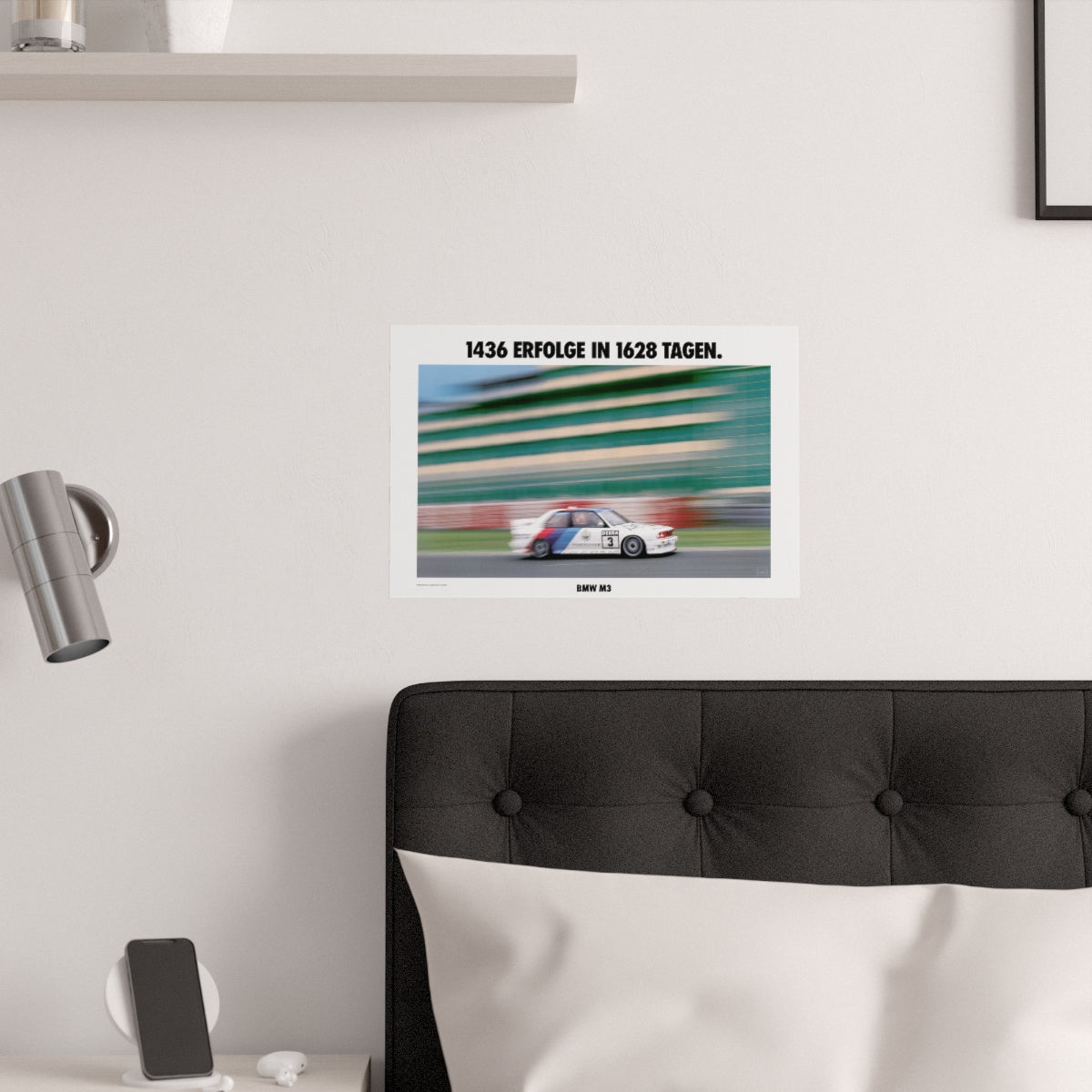 BMW E30 M3 race car shown in motion, racing on a track. Title above the photo reads "1436 successes in 1628 days". The poster is displayed in a white bedroom and placed over dark gray headboard.