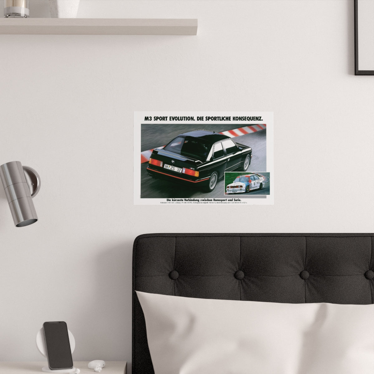 Black BMW E30 M3 Sport Evolution shown in motion, on a racing track. In the lower right corner is a similar picture of an E30 M3 race car. Title above the photo reads M3 Sport Evolution - The Sporting consequence. The poster is displayed in a white bedroom and placed over dark gray headboard.