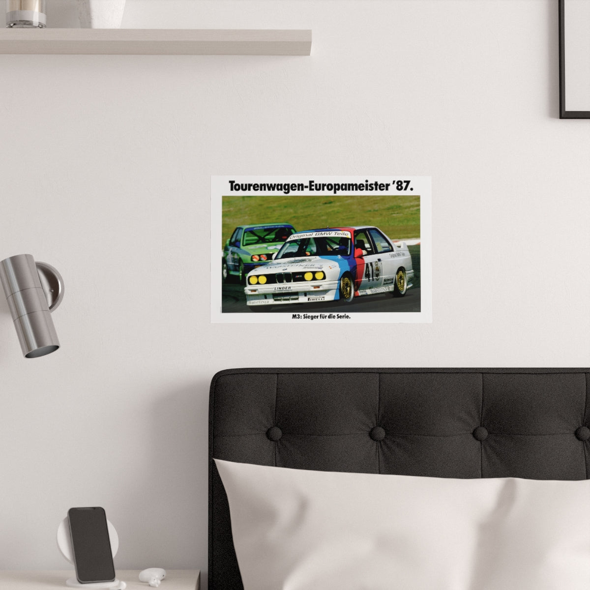 BMW E30 M3 shown in motion, racing on a track. Title above the photo reads European Touring Car Champion 1987. The poster is displayed in a white bedroom and placed over dark gray headboard.