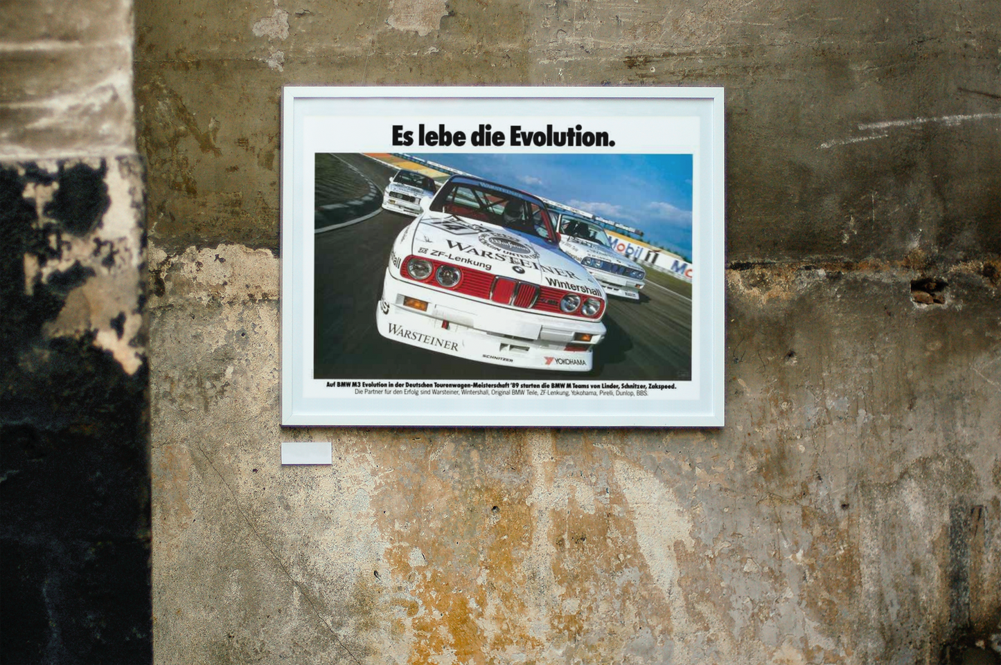 Three BMW E30 M3 race cars shown in motion, racing on a track. Title above the photo reads Long live Evolution. The frame is displayed on a beautiful concrete wall.